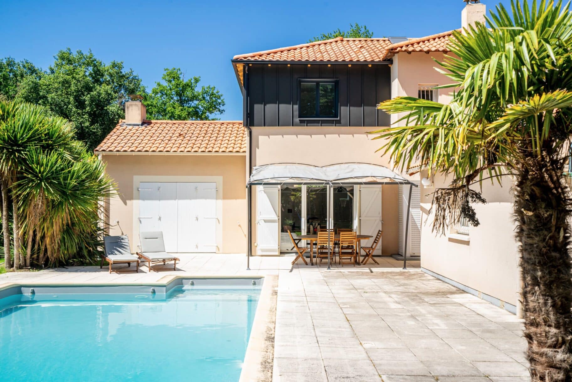 Vue extérieure d’une maison à Basse-Goulaine avec surélévation en ossature bois et piscine rénovée